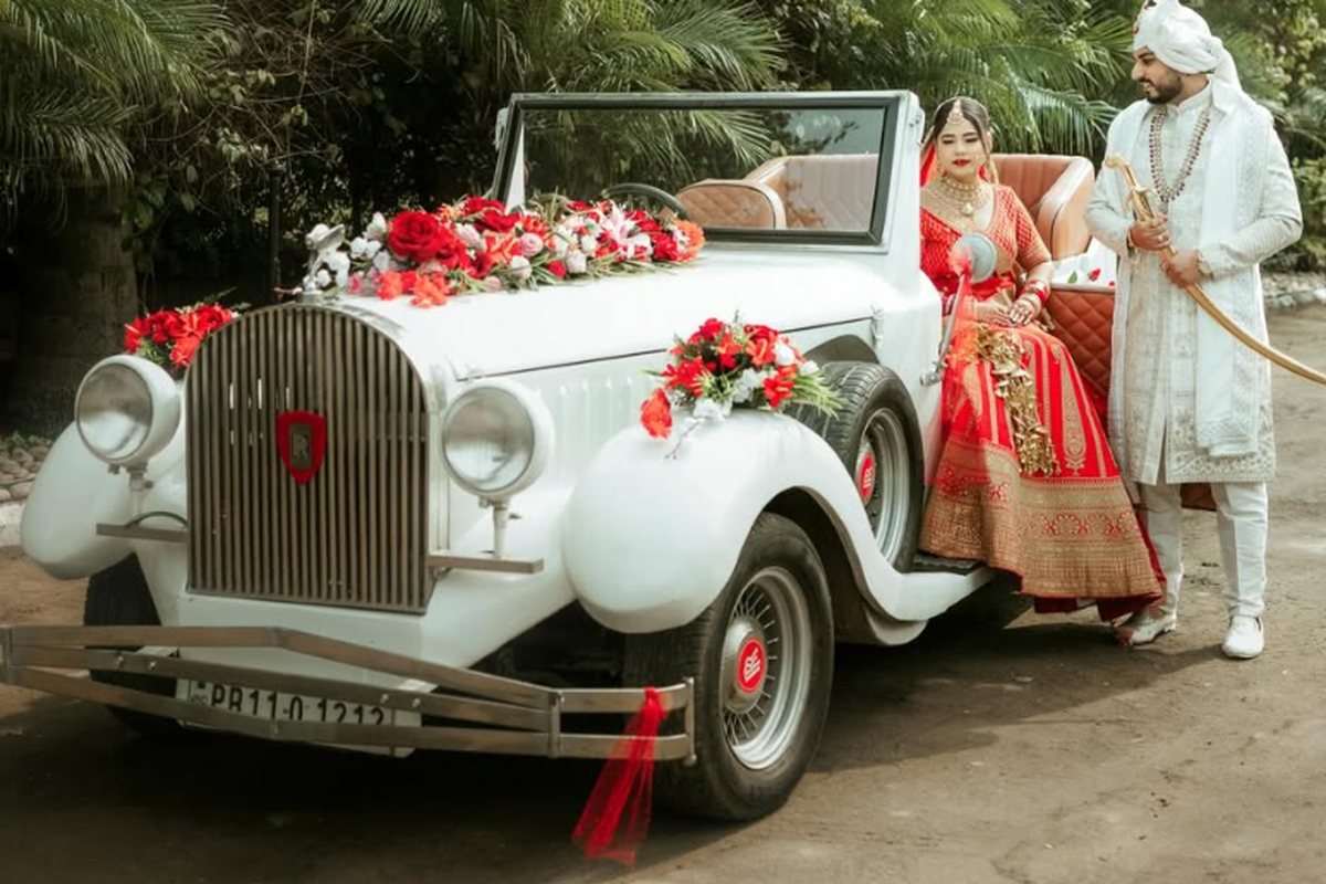 Bride and groom beside a flower-decked vintage car